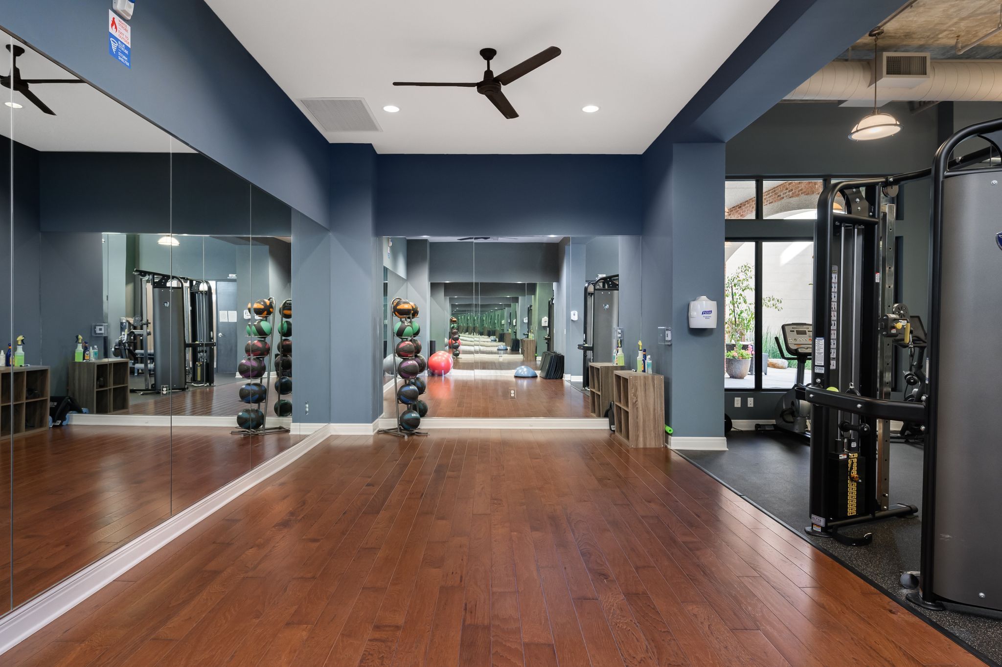 Mission 106 Luxury Apartments fitness center with a large open wood floor for working, exercise equipment, and a ceiling fan