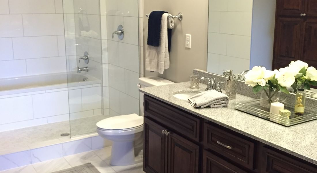 Mission 106 Luxury Apartments spacious bathroom with a standing shower, glass enclosure, and large vanity mirror, counter, and cabinets for storage