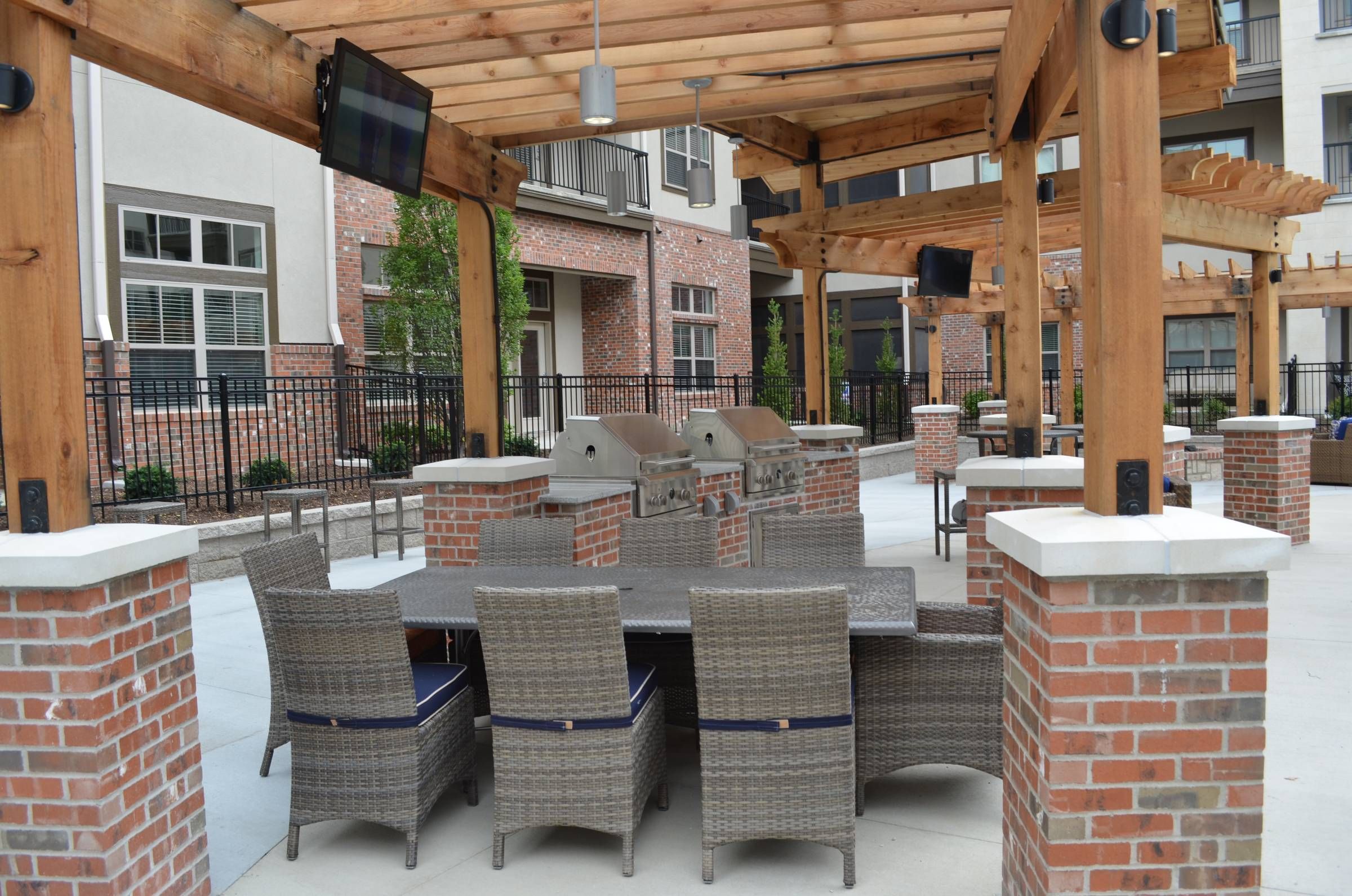 Mission 106 Luxury Apartments poolside courtyard with cabana, TV, and casual outside dining area