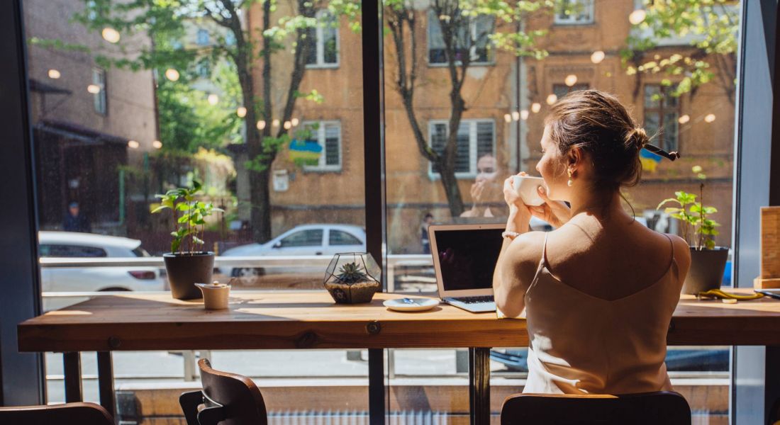 Mission 106 Luxury Apartments in Leawood, KS neighborhood with woman drinking coffee while sitting near the window in modern cafe and coffee bar