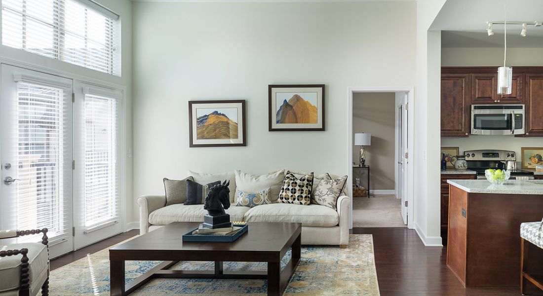 Mission 106 Luxury Apartments living room with floor-to-ceiling windows, natural light, vinyl plank hardwood-style flooring, couch, coffee table, and wall art
